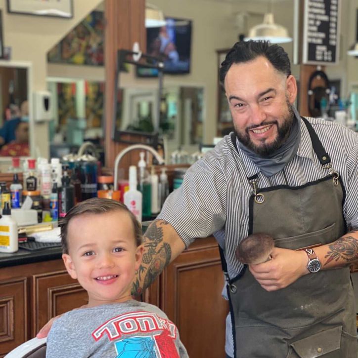 Emilio grinning with a young regular in the chair